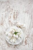 Gesprenkelte Ostereier und weiße Blüten auf einem Teller