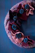 Knitted wreath decorated with pieces of felt and blue-painted larch cones