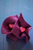 Small wooden hearts in squares of felt on blue surface