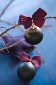 Black Christmas-tree bauble with felt ribbon on bare branch