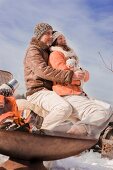 Mann und Frau kuscheln beim Winter-Picknick in verschneiter Landschaft