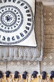 Two cushions with different patterns on ethnic fringed rug