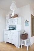 Basket on step stool next to white, vintage dresser