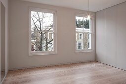 Renovierte elegante Raumecke mit minimalistischer raumhoher Schrankwand und Parkettboden