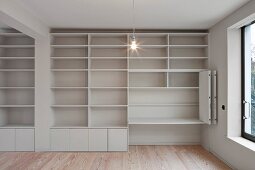 Empty, white minimalist fitted cabinet with shelves and folding sliding doors