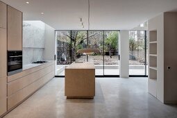 Elegant, open-plan, designer-style kitchen with island counter and view into garden