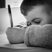 A little boy writing on a sheet of paper (black-and-white shot)
