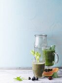Two green smoothies garnished with parsley and celery sticks