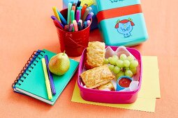 Snack box with filled puff pastry, grapes and tomato sauce