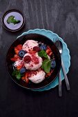 Raspberry yoghurt ice cream with raspberries, blueberries, strawberries and mint served with raspberry sauce