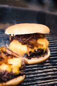 A hamburger with cheese and toasted onions on a grill