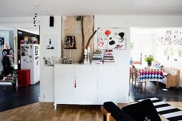 White sideboard between open doorways leading into dining room and kitchen in open-plan interior