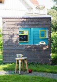 Saucepan on rustic wooden stool in front of wooden playhouse