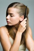 A dark blonde woman combing her hair