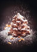 A chocolate pine cone with icing sugar and pine nuts