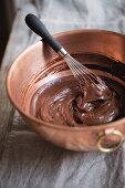 Chocolate glaze in mixing bowl with a whisk
