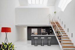 Steel staircase with wooden treads leading to white gallery level above charcoal-grey kitchen