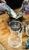 Oyster water being sieved into a jug