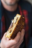 A man holding a ham and cheese toasty