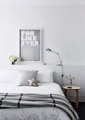 Double bed with bedspread and pillow in front of bed head with storage space
