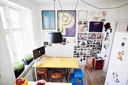 Yellow table, various stools, collection of photos and framed posters in dining area