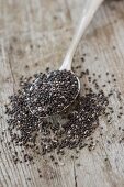 Chia seeds on a spoon and on a wooden surface