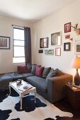 Dark grey couch and coffee table on black and white cowhide rug in corner of living room