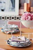 Schwarz-weisses Gedeck mit Stoffserviette und Schale mit rosa Blüten auf Esstisch