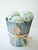 Mint chocolate chip ice cream in a tin bucket with raffia and a spoon