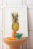 Kork-Beistelltisch mit Keramikschalen und Vase vor Bild mit Ananasmotiv