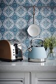Retro Teekessel und Toaster auf Küchenzeile vor blau-weisser Tapete