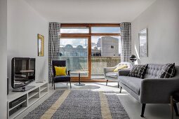 Retro sofa and armchairs in front of open balcony door in living room