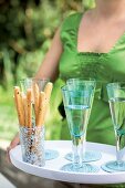 A woman serving breadsticks and sparkling wine