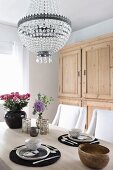 Table set for two below chandelier with glass pendants in rustic, elegant dining room