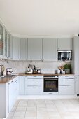 Fitted kitchen with pale grey cupboards and beige tiled floor