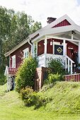 Schwedisches Holzhaus mit weissen Giebelbrettern in ländlicher Umgebung
