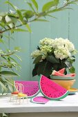Hand-made, watermelon-slice invitation cards made from folded paper on garden table