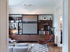 Schrankwand mit Regalsystem und Schiebeelement in elegantem Wohnzimmer mit Retro Ledersessel