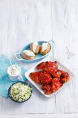Barbecue chicken wings and legs, coleslaw with cucumbers, and jacket potatoes with tzatziki