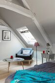 Armchair and three-legged table below skylight in bedroom