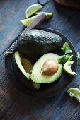 Avocados, ganz und halbiert mit Messer auf Teller