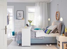 A boxspring bed with a bridge bed in a bedroom in shades of blue