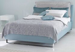 A boxspring bed in blue tones in a bedroom