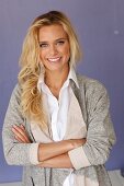 A young blonde woman wearing a white blouse and a grey shirt jacket