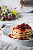 Strawberry compote being poured over buttermilk pancakes