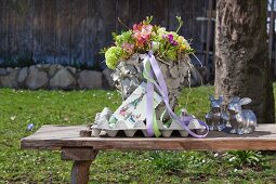 Flowers in vase covered in pieces of cardboard on table outside