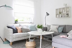 White coffee table and sofas with different covers below window with closed blind in corner of living room