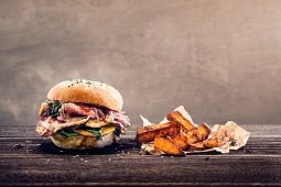 A sesame seed roll with flank steak, red onions and spinach served with sweet potato chips