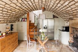 Wohnküche mit rustikaler Gewölbedecke, weißen Einbaumöbeln und gewendelter Holztreppe