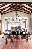 Black dining table and chairs on terracotta floor tiles in open-plan interior